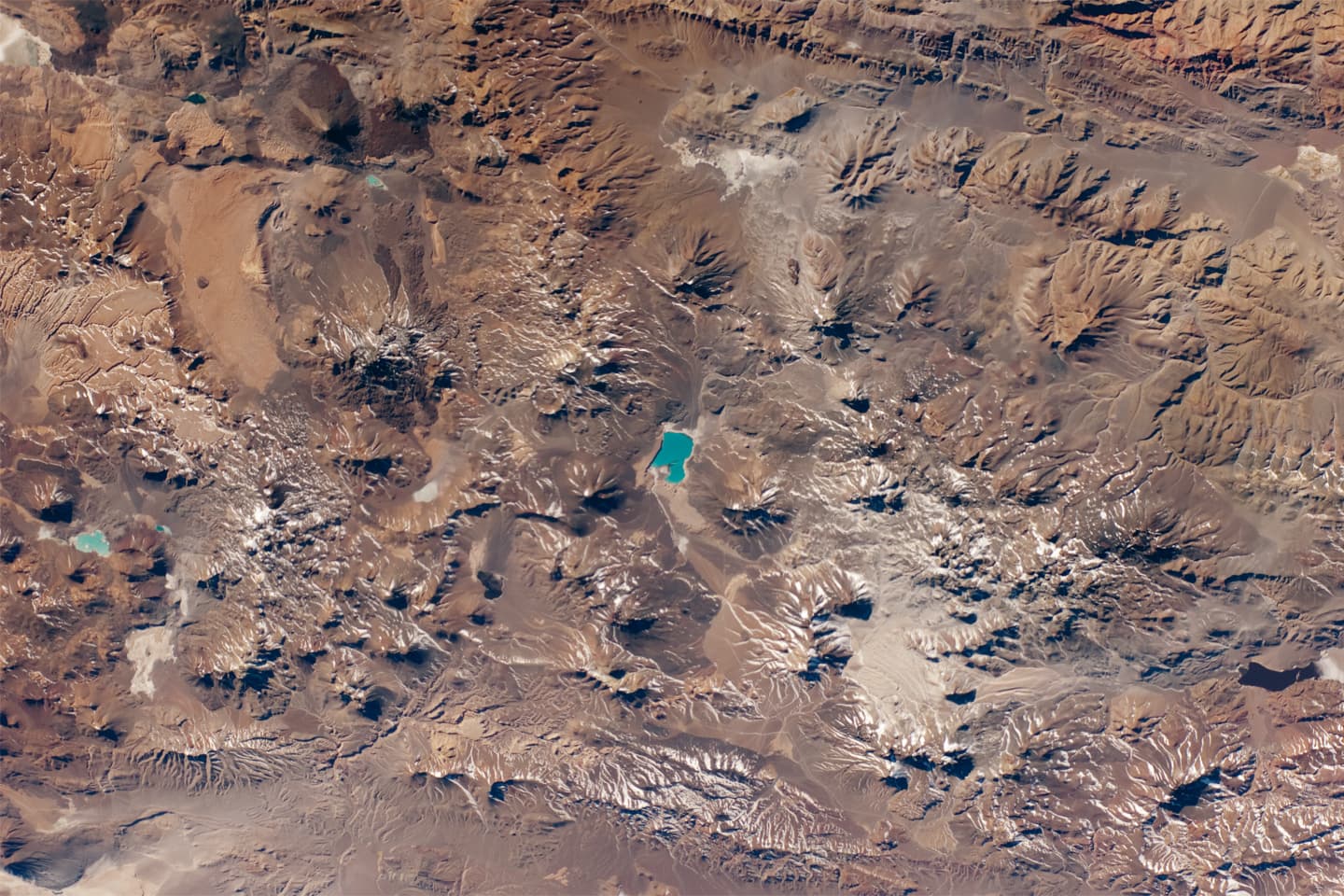 Astronaut photograph of volcanic cones, lava flows, tuff sheets, and Laguna Verde in the central Andes.